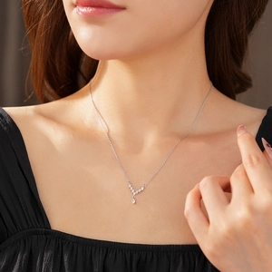 Detail of silver V-shaped necklace with teardrop and leaf pendants worn by model