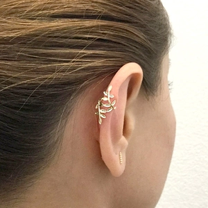 Close-up of 18k gold-plated leaf ear cuff and small stud earring on woman's left ear