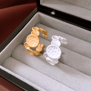 Detail of matte gold and white textured oval disc rings set in a velvet jewelry box