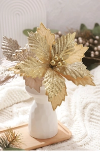 Close-up of gold and silver velvet Christmas flowers with glitter on a white vase