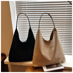 Minimalist faux suede hobo tote bag in beige and black on a sunny window sill