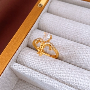 Macro detail of 24K gold plated ring featuring crown fleur-de-lis and teardrop zircon