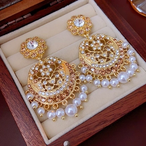 Close-up of vintage gold earrings with champagne rhinestones and white pearl fringe