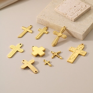 Detailed view of nine gold titanium steel cross pendants in various shapes on beige stone