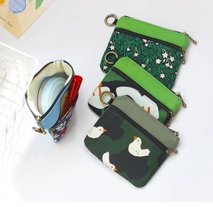 Détail de la pochette en tissu vert montrant les doubles fermetures éclair et le stockage