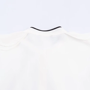 Detail of white shirt collar with elegant black piping trim and layered decorative design