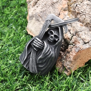 Macro shot of retro stainless steel Grim Reaper bell pendant on natural wood background