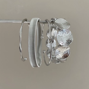Set of four silver geometric bangles featuring hammered, ribbed, and knotted textures