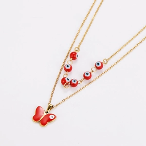 Detail of gold double-layer necklace with red evil eye beads and butterfly pendant