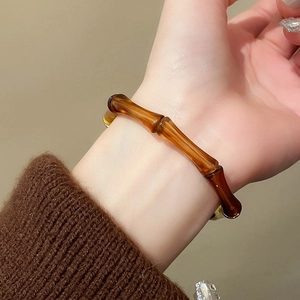 Close-up of amber resin bamboo-joint bangle worn on a wrist with a brown sweater