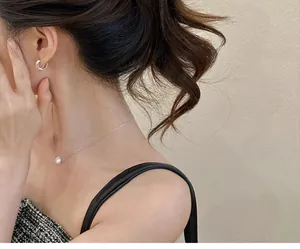 Modèle élégant portant un collier pendentif perle et un ensemble de créoles argentées