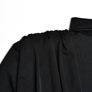 Close-up detail of black fabric shoulder showing elegant drape and pleated design features