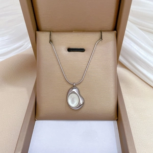 Silver snake chain necklace with cat eye stone pendant displayed in a gold jewelry box