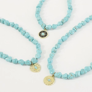 Close-up of Bohemian turquoise bead necklaces with gold sun, heart, and evil eye pendants