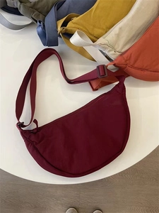 Flat lay of multi-color nylon crescent crossbody bags in burgundy, yellow and navy