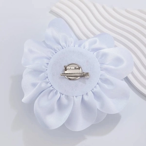 Detail showing back of white fabric rose with metal safety pin and duckbill hair clip