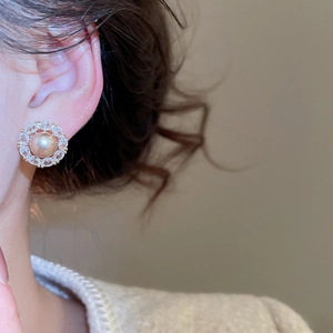 Macro detail of elegant champagne pearl stud earring with zircon flower petals on model