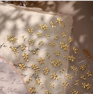 Macro detail of gold foil embossed flower nail stickers with vintage floral patterns