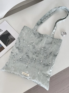 Silver velvet tote bag with pearl accents and white stitching on a clean tabletop