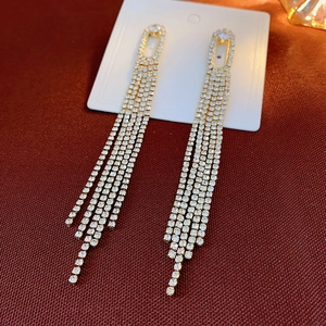 Close-up of golden tassel drop earrings with sparkling rhinestones on red background