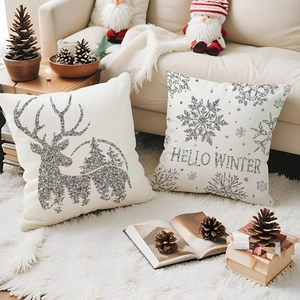 Détail de deux housses de coussin de Noël avec renne et flocons de neige pailletés d'argent