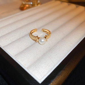 Macro shot of an adjustable gold-plated ring with a white pearl on a white velvet display
