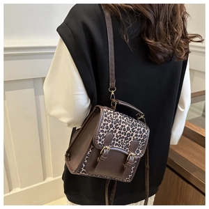 Detail of a mini leopard print and brown leather backpack with retro buckle straps