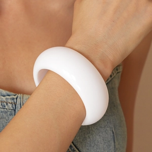 Close-up of a chunky white resin geometric bangle worn on a wrist for a modern look