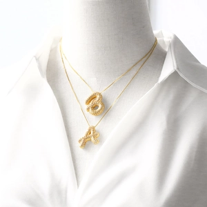 Colliers pendentifs lettres A et B dorés avec texture pavée sur mannequin femme