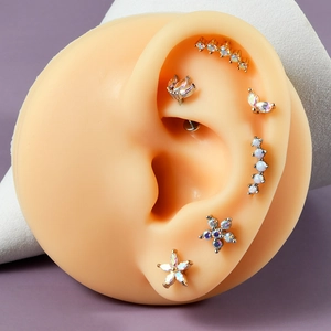 Macro shot of stainless steel labret studs with opal stones on a silicone ear model