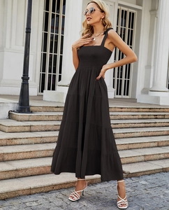 Detail view of the black sleeveless tiered maxi dress with elegant ruffles on stairs