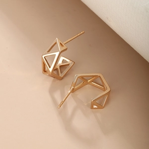 Macro shot of geometric hollow gold earrings with mirror polish finish and stud backing