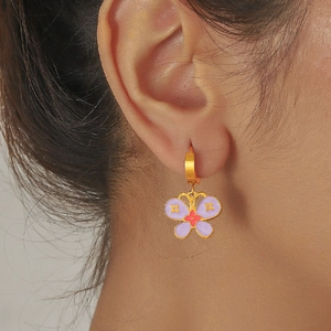 Détail d'une boucle d'oreille papillon dorée avec émail violet portée par un mannequin
