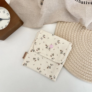Detailed close-up of floral canvas pouch with pink snap button and brand label