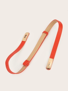 Detail of bright orange slim belt featuring a gold-tone metal twist lock buckle closure