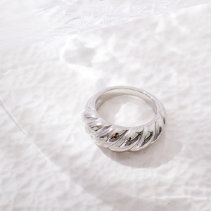 Macro shot of silver twisted croissant ring with high polish finish on white texture