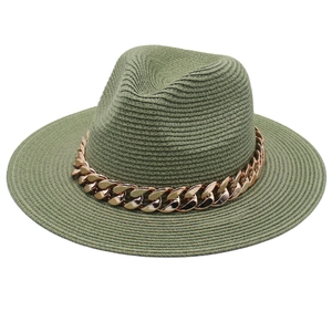 Détail d'un chapeau fedora en paille vert olive avec une élégante chaîne en or rose