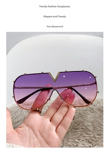 Detail of V-shaped gold metal bridge and gradient lenses on oversized sunglasses