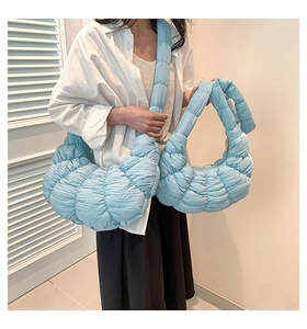 Light blue quilted cloud bag in medium and small sizes shown in a cozy indoor setting