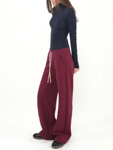 Detail of high-waist burgundy wide-leg trousers with contrast drawstring and side pockets