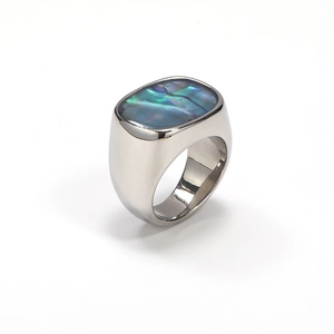 Macro detail of oval abalone shell inlay on a polished silver titanium steel ring