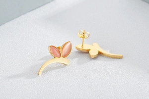 Macro shot of gold floral earrings featuring pink cat eye stones and leaf-shaped design