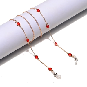 Elegant gold metal eyewear chain featuring red crystal beads and clear rubber grips