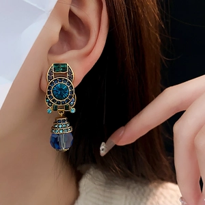 Macro detail of vintage gold-tone clip earrings with blue and green crystals on model