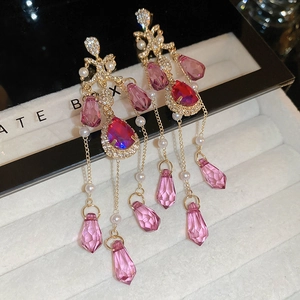 Macro shot of gold tassel earrings with pearls and purple crystals in a gift box