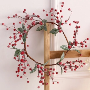 Ghirlanda natalizia con bacche rosse e neve finta su un supporto in legno rustico