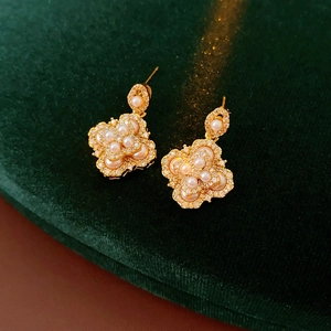 Gros plan détaillé de boucles d'oreilles trèfle plaquées or avec perles et cristaux zircon