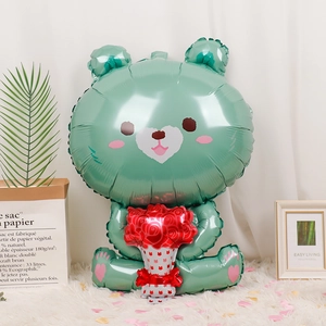 Detail of mint green sitting bear foil balloon holding red flowers on a plush rug