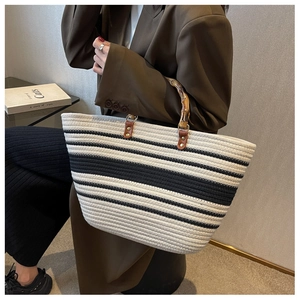 Detailed shot of striped woven tote bag with natural bamboo handles held by model