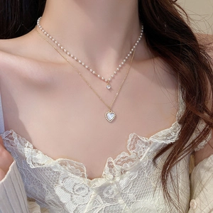 Close-up of double-layer necklace with pearl strand, heart pendant and zircon stones
